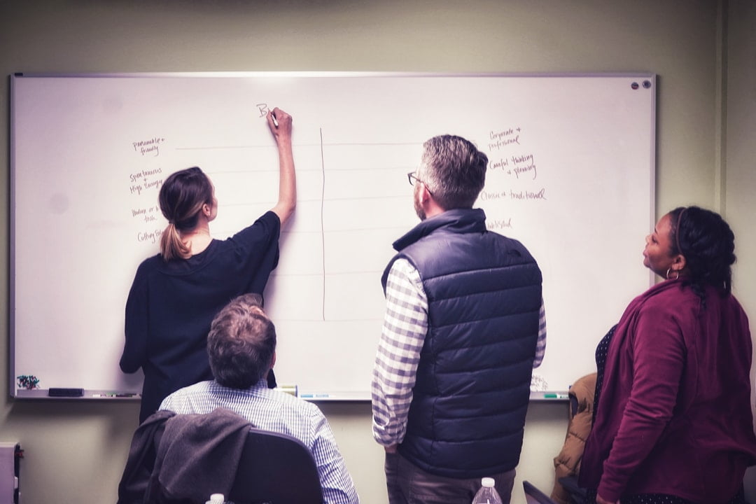 Mighty Ally Co-founder Kathleen Souder writing at a whiteboard with the Barefoot Republic team.