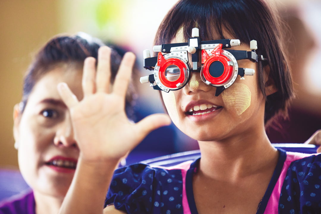 Young girl wearing phoropter during an eye examination.